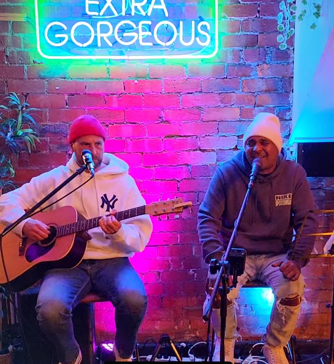 Wiz and Dash performing live under the glowing Extra Gorgeous neon sign