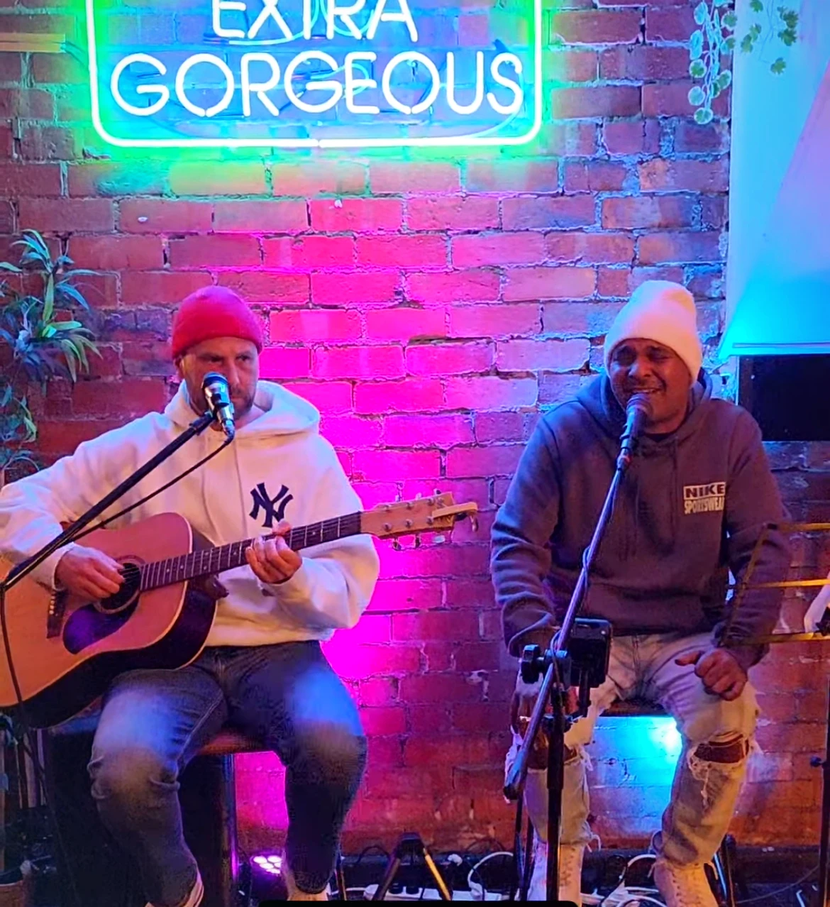 Wiz and Dash performing live under the glowing Extra Gorgeous neon sign